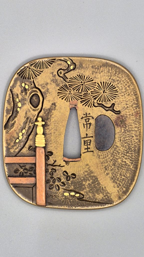 The signed back: a pine trunk with an oval knot-hole at the left, radiating needle clusters above, a copper post with a gold finial and small plants below, the signature Tsuneshige beside the tang opening.