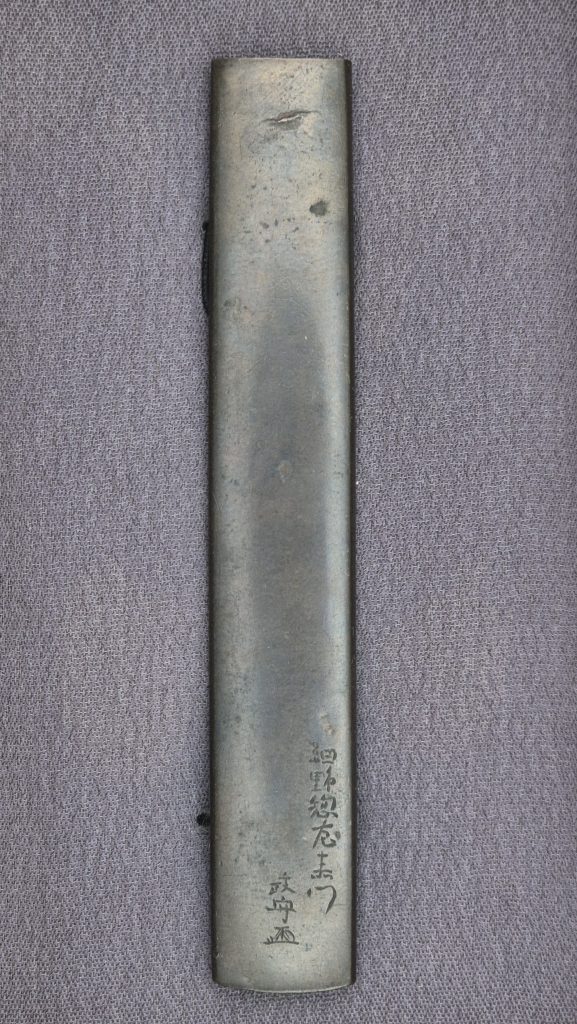 The back of the kozuka in its box, signed Hosono Sozaemon Masamori with kao.