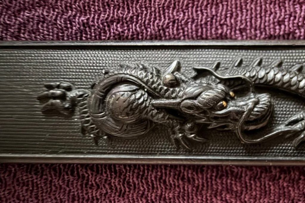 Detail of the dragon's head with gold eyes, turned toward the jewel.