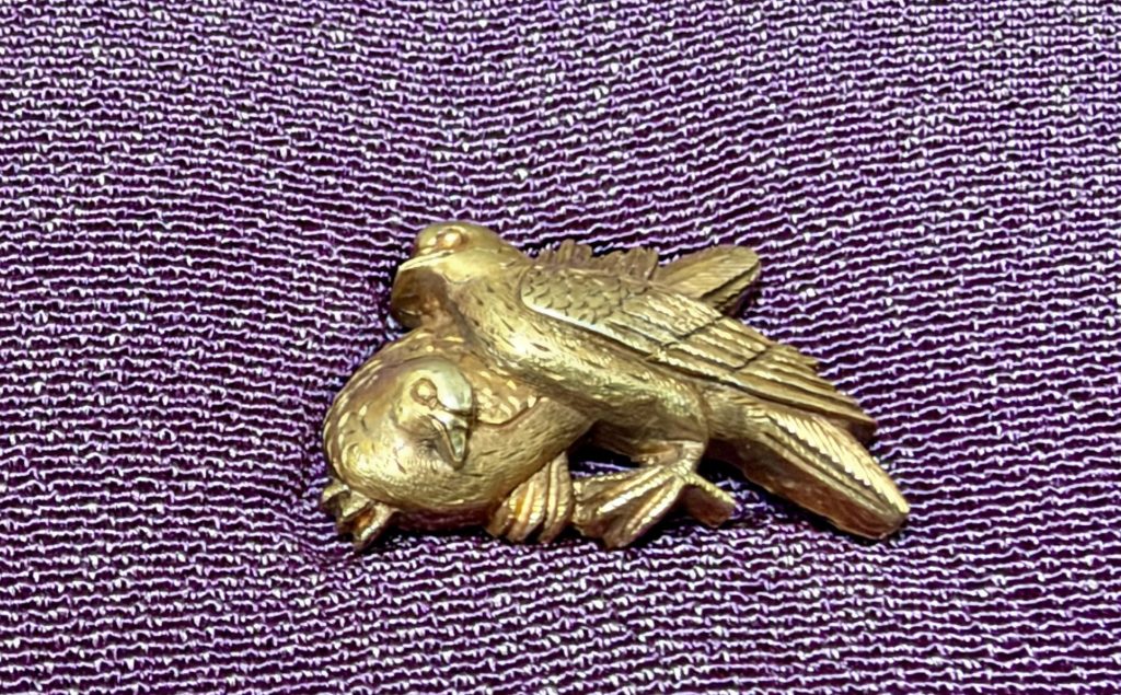 The other menuki: one dove turns its head toward the viewer while the second stands over it, wings half open and every feather cut separately.