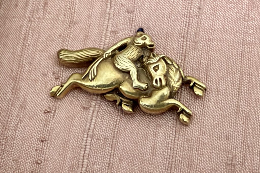 One menuki: a monkey crouches on the back of a galloping horse, while the horse turns its head back toward it, mane flying.
