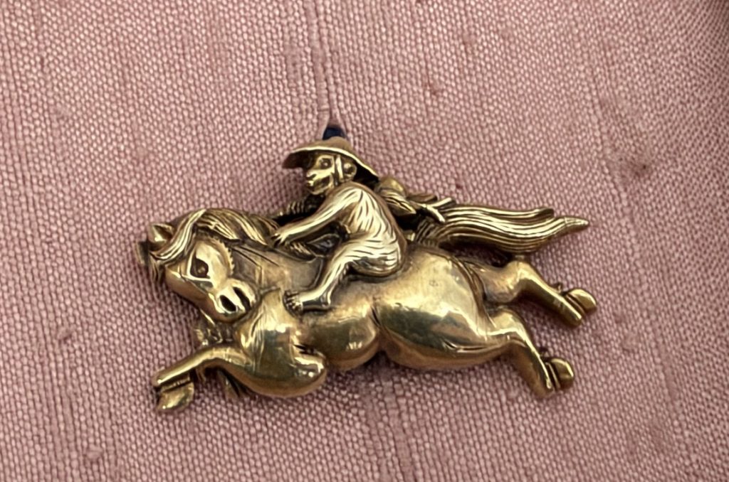 The other menuki: a monkey in a wide hat sits upright on a running horse, one hand in its mane, the tail streaming behind.