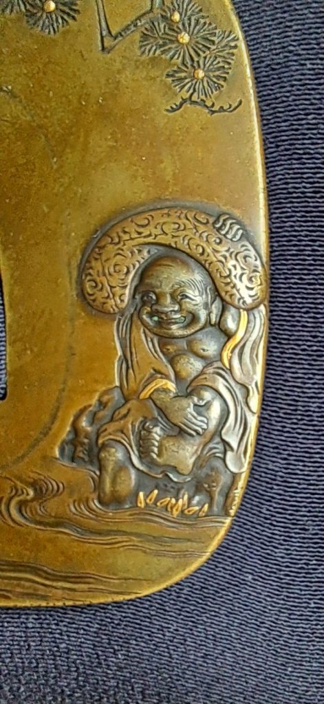 Detail: Hotei's laughing face and round body, his scroll-patterned sack behind him, his feet at the edge of the water.