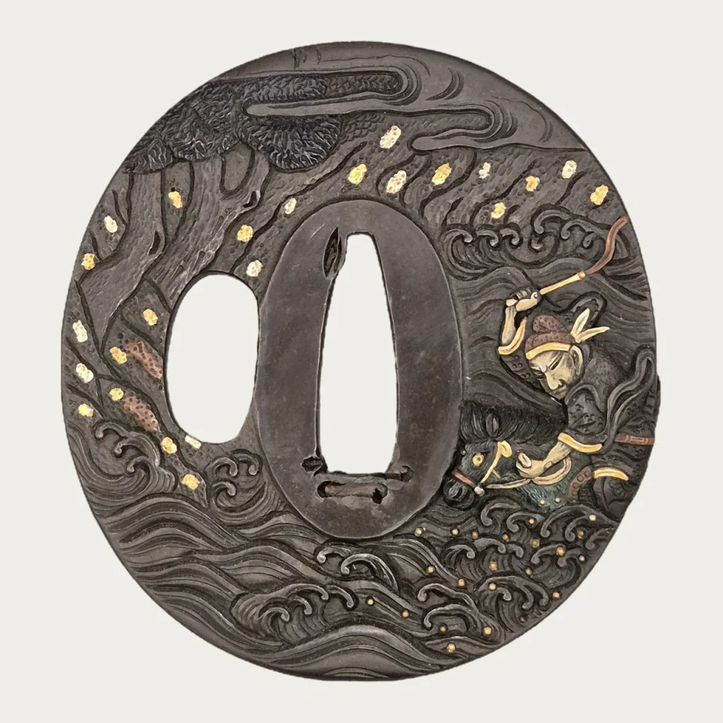 The Hamano Naoyuki tsuba: a rider in high relief drives his horse through breaking waves on the right, a pine at the upper left, gold spray across the dark plate.