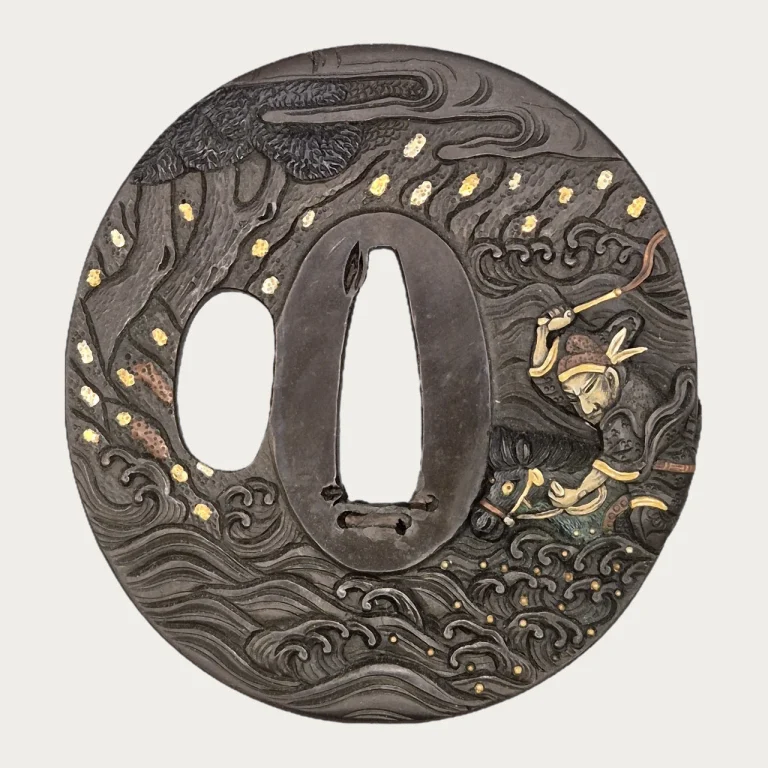 The Hamano Naoyuki tsuba: a rider in high relief drives his horse through breaking waves on the right, a pine at the upper left, gold spray across the dark plate.