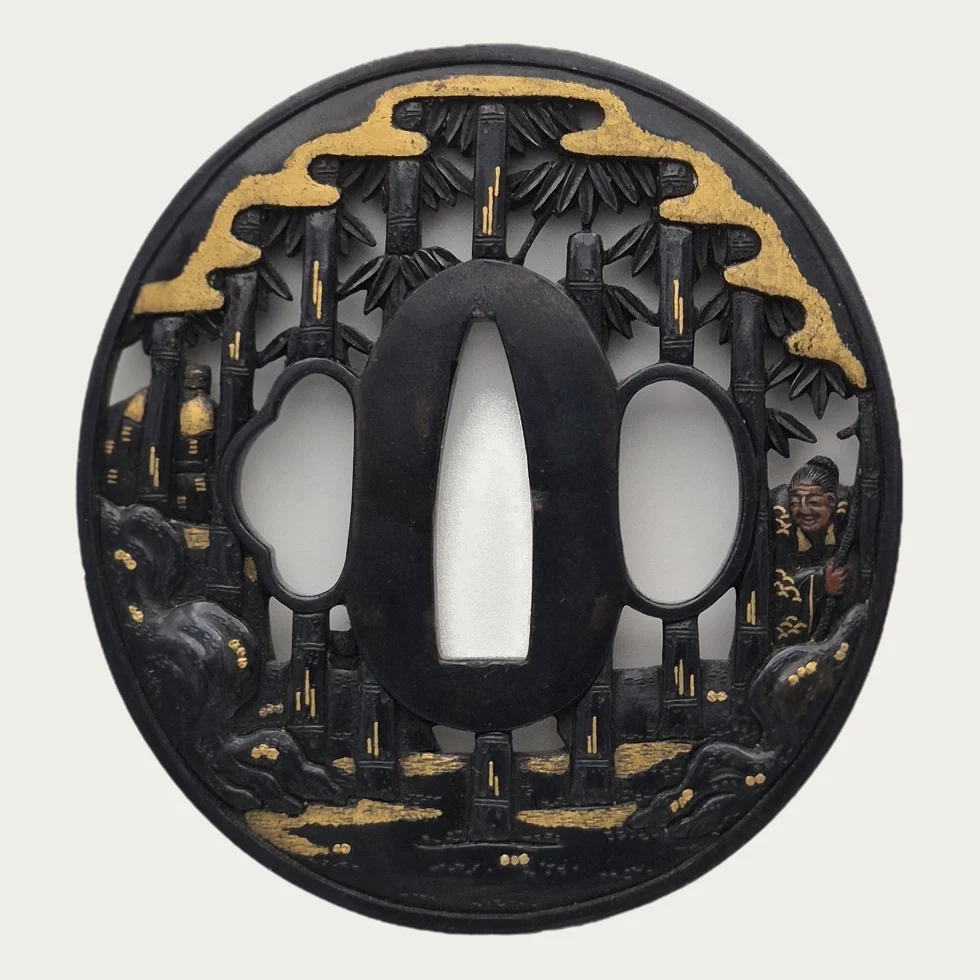 The back of the tsuba, where the bamboo and the gold clouds continue around the oval plate and one of the sages shows from behind.