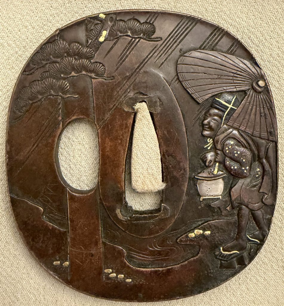Aridoshi tsuba in sentoku under a reddish patina: an old man in a black cap walks through slanting rain under a large paper umbrella, a lantern in his hand; at the left an upright post rises past a pine.